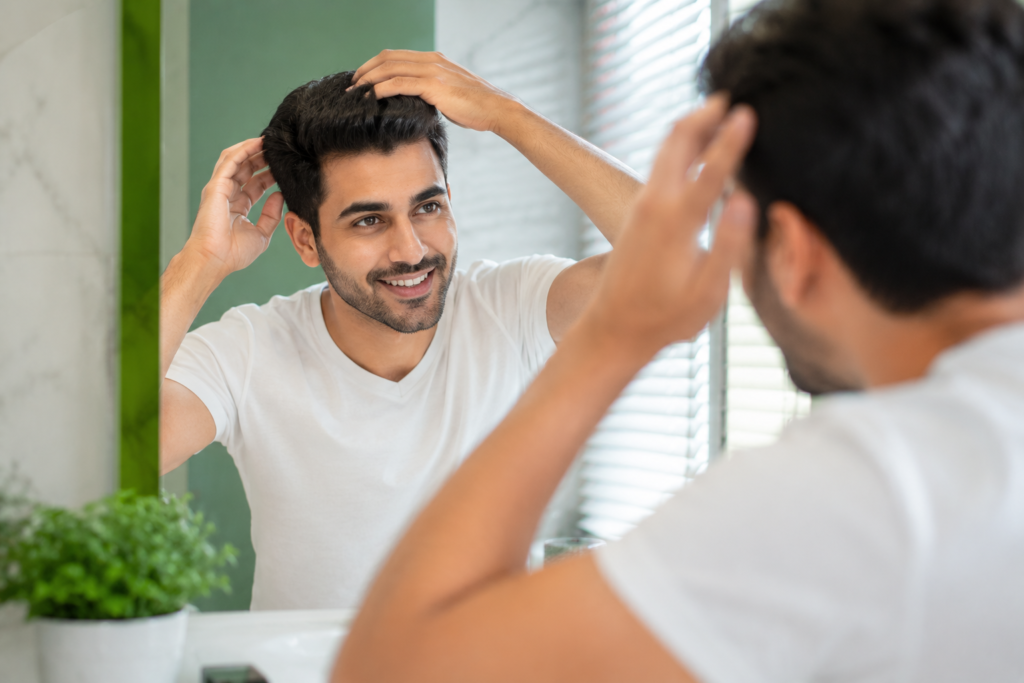 Man confidently styling his hair after getting a hair system
